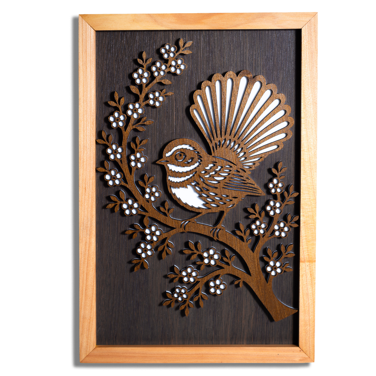 Fantail pīwakawaka layered timber wall art in a macrocarpa frame, front view