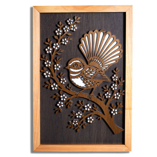 Fantail pīwakawaka layered timber wall art in a macrocarpa frame, front view